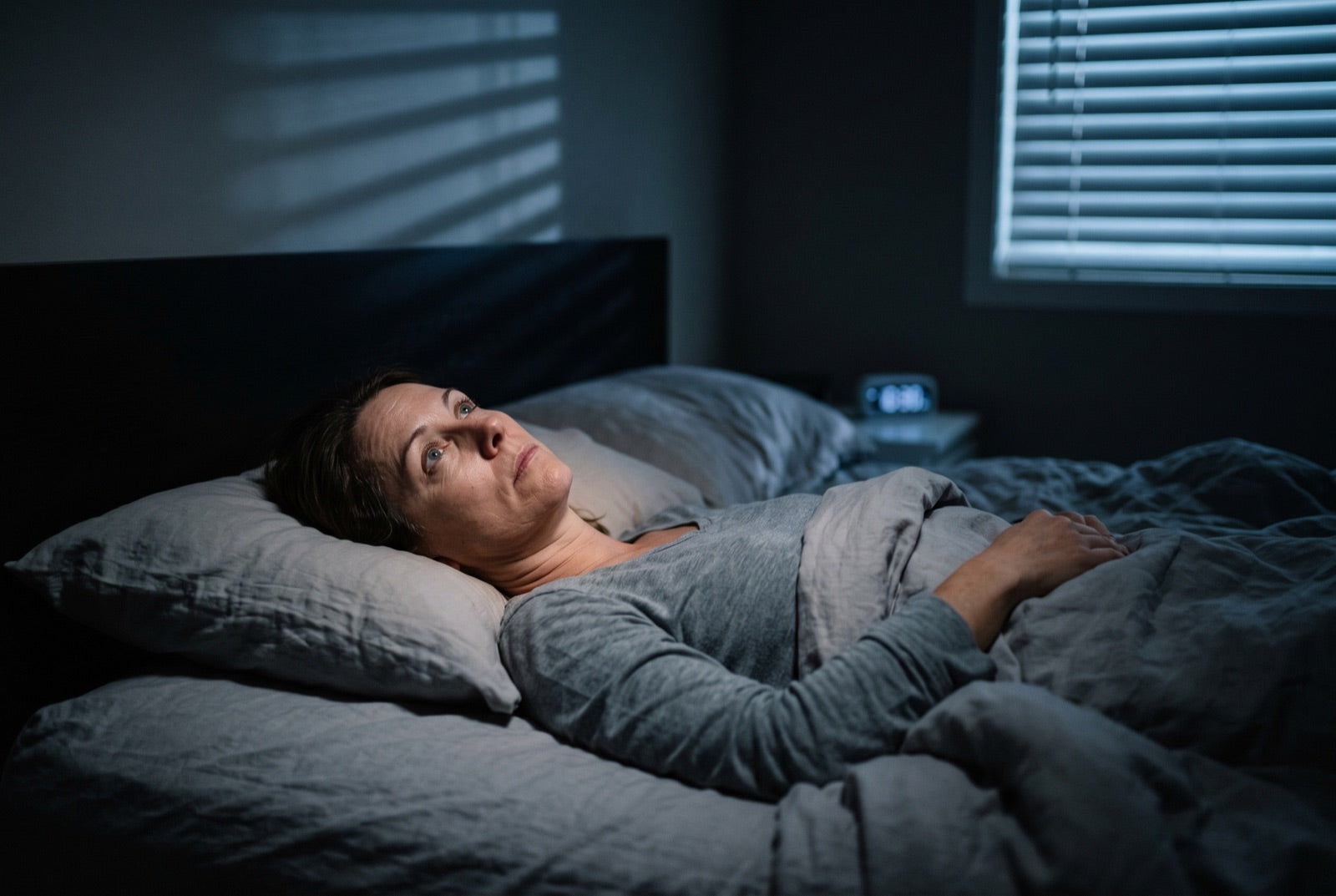 A woman lying awake in a dark bedroom in the middle of the night